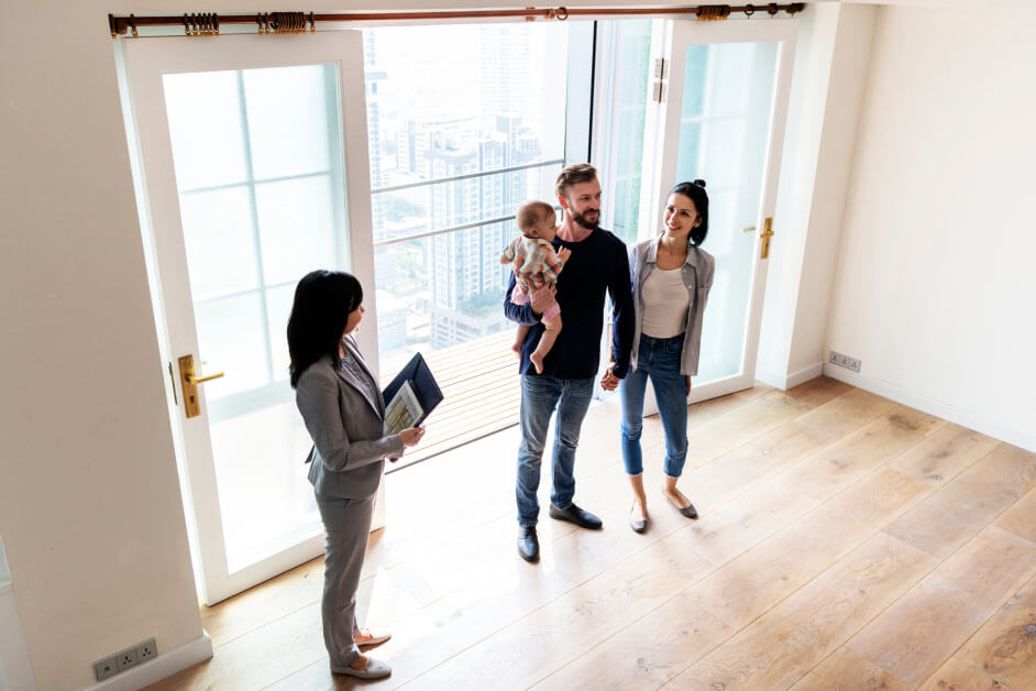 Couple and child tour home for sale during open house with real estate agent.