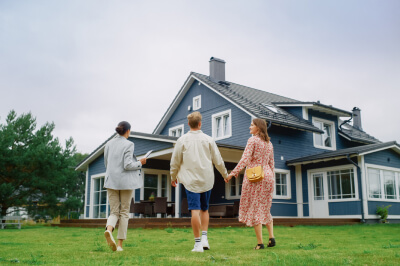 Couple tours outside of house for sale with their real estate agent.